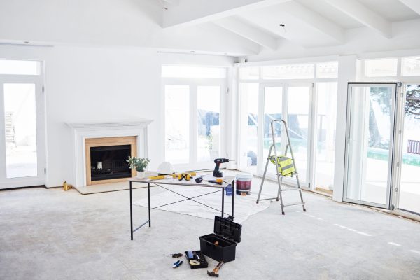 Shot of building plans and equipment on a table in an empty living room during the day.